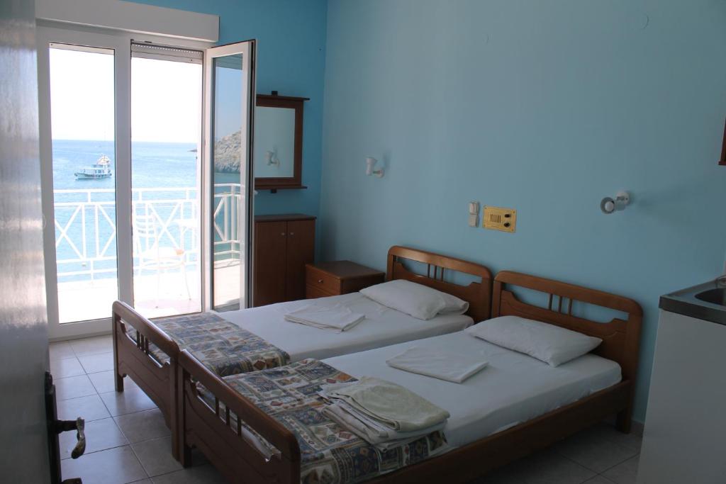 two beds in a room with a view of the ocean at Elena Studios in Tarti