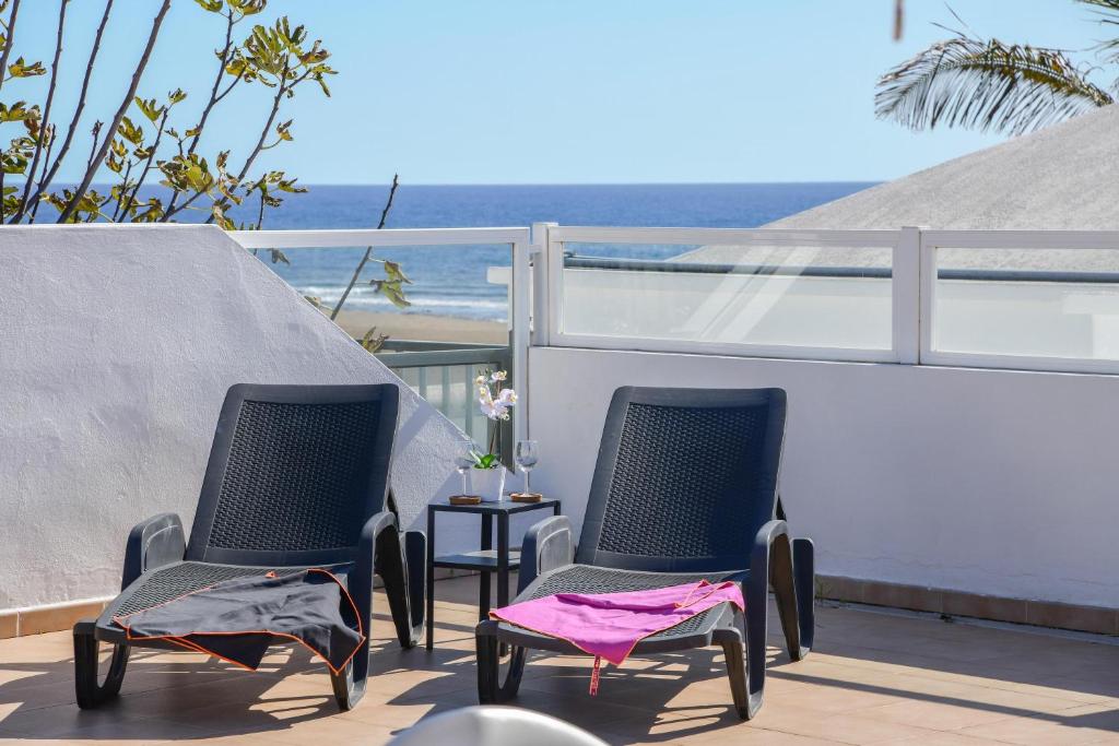 Duas cadeiras numa varanda com vista para o oceano em Casa Conchita em Playa Honda
