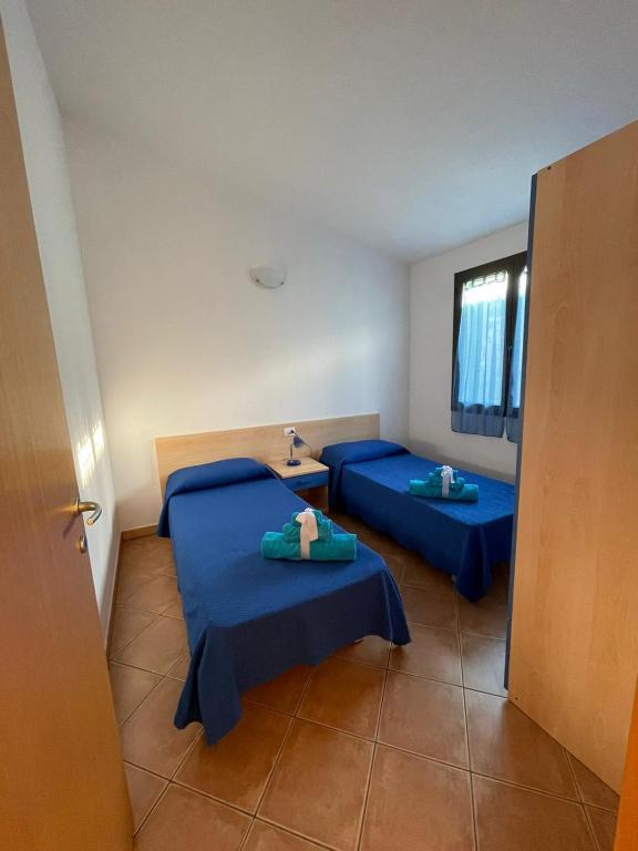 dwa łóżka w pokoju z niebieską pościelą w obiekcie Case Vacanze Sole e Luna w mieście Budoni