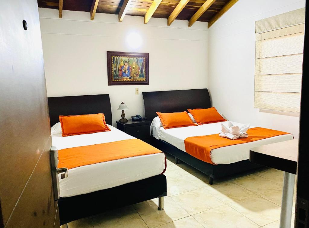 2 camas en una habitación con naranja y blanco en Hotel Palma 70 en Medellín
