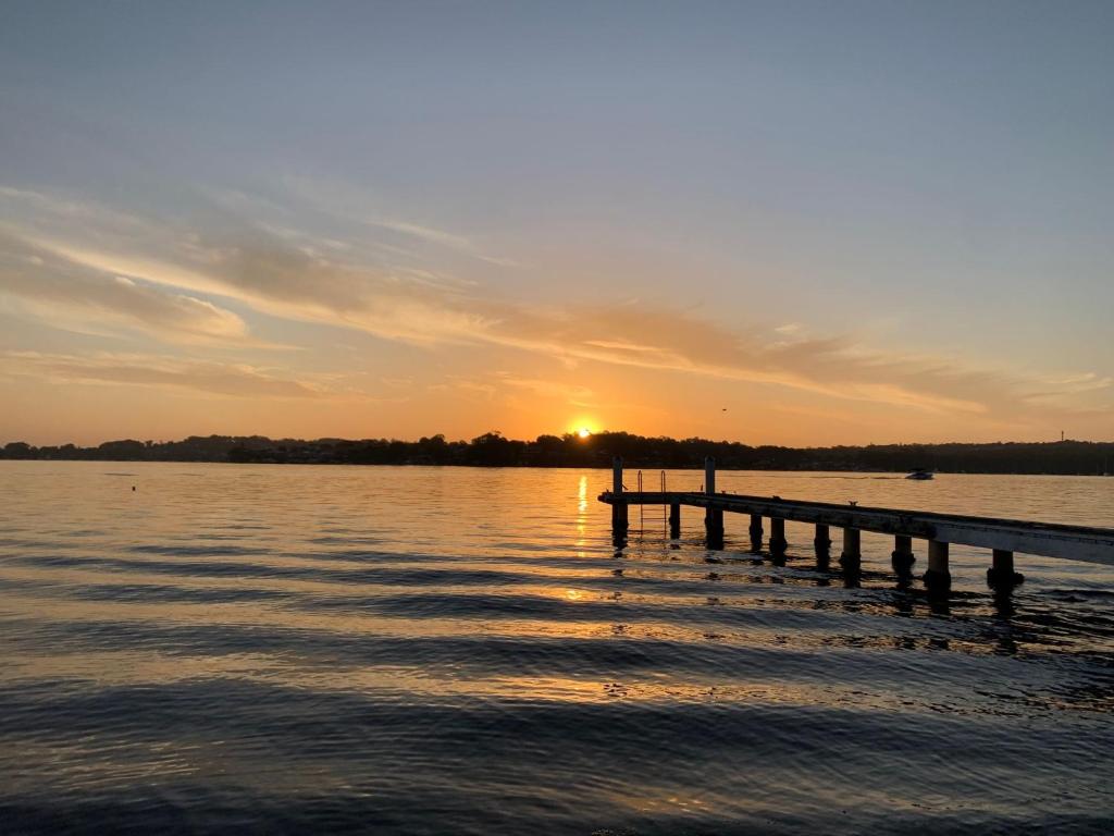 un muelle en un lago con puesta de sol en Sealand Lake House Stunning Absolute Waterfront, en Fishing Point