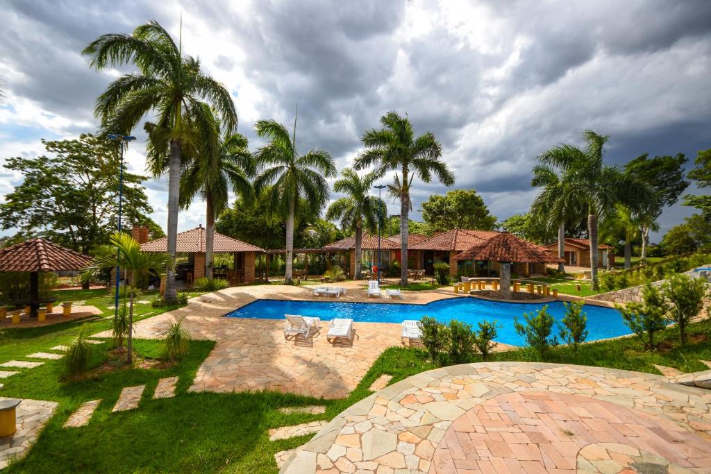 um resort com piscina e palmeiras em HOTEL ABAPORU em Adamantina