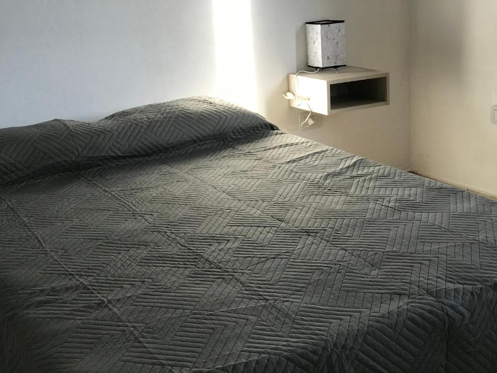 1 cama con edredón gris en un dormitorio en Departamentos Alberdi 3 en San Rafael