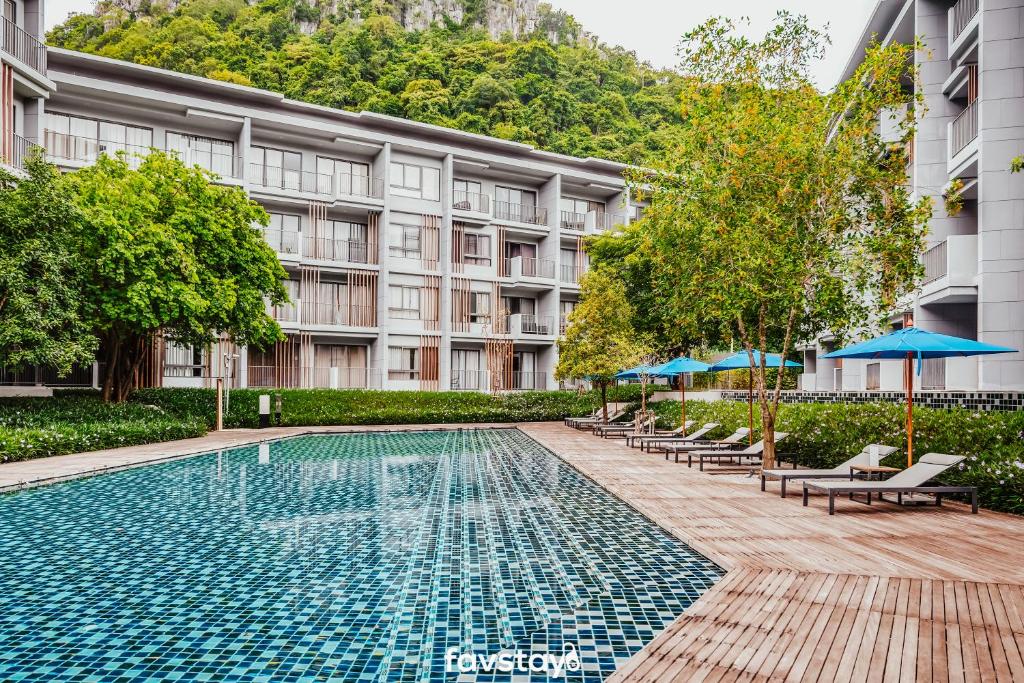 a swimming pool with chairs and umbrellas in front of a building at 23 Degrees Khao Yai by Favstay in Phayayen