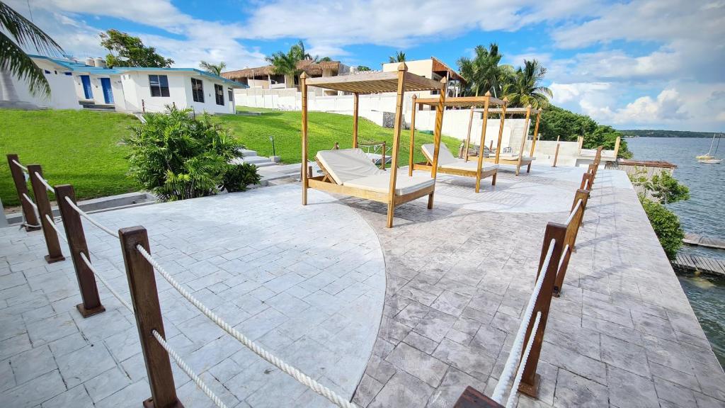 ein Dock mit Stühlen und ein Regenschirm neben dem Wasser in der Unterkunft Hotel Vista Laguna Bacalar in Bacalar