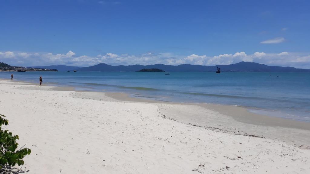 a white sandy beach with people in the water at Sol da Cachoeira in Florianópolis