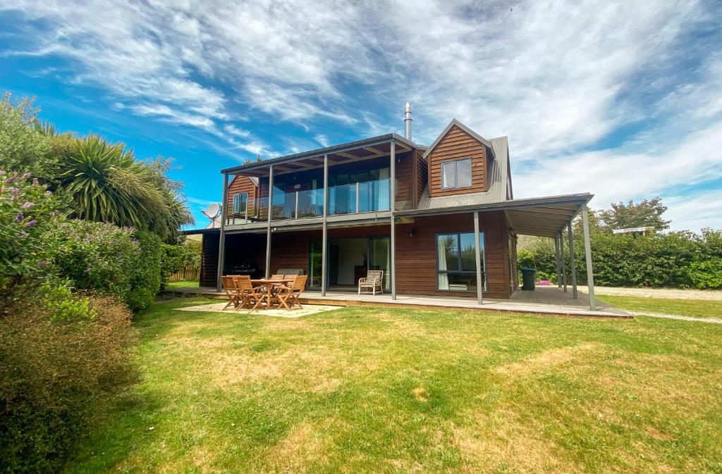 une grande maison avec des fenêtres en verre sur une pelouse dans l'établissement Stunning Panoramic Lake Hawea Views 5 Bedrooms, à Lake Hawea