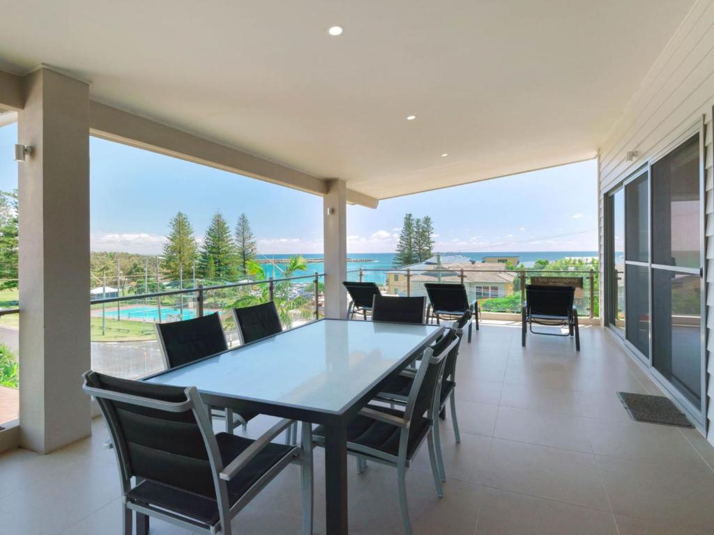 a dining room with a table and chairs on a balcony at Bimbadeen Penthouse in Yamba