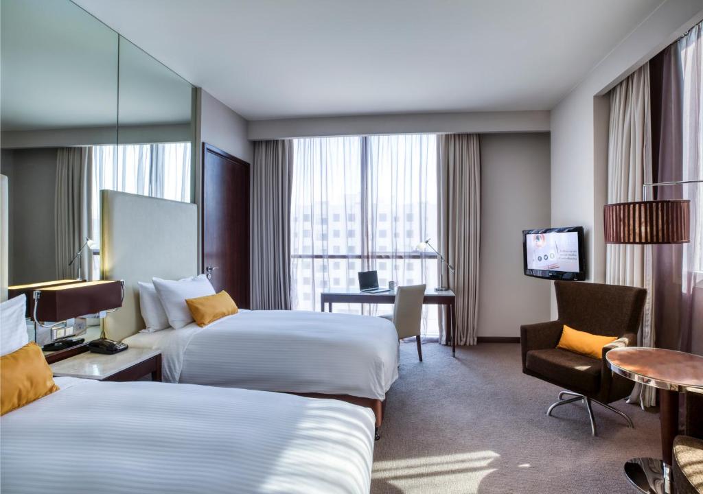 a hotel room with two beds and a television at Centro Barsha - by Rotana in Dubai