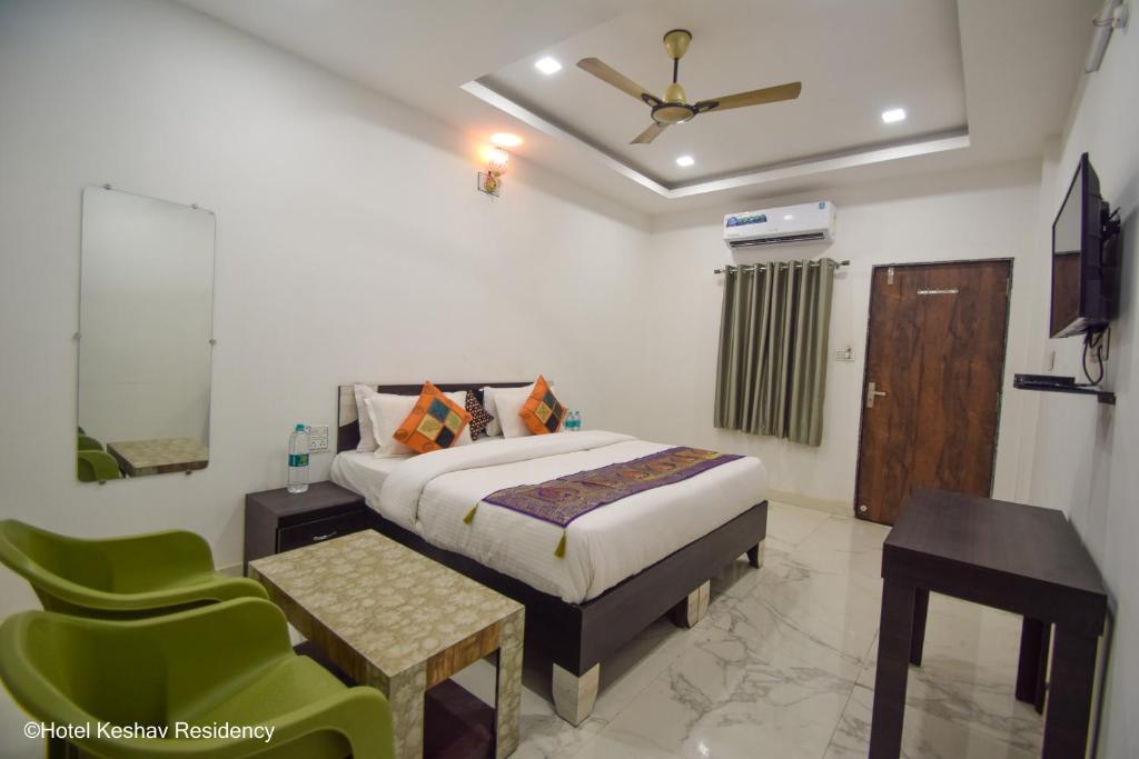 a bedroom with a bed and a table and a chair at Hotel Keshav Residency in Chittaurgarh