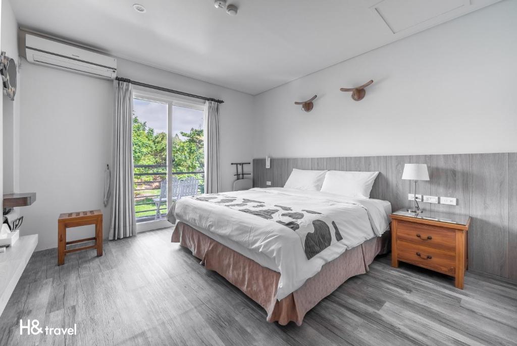 a bedroom with a large bed and a large window at Fairyland & Farm Guest House in Kenting