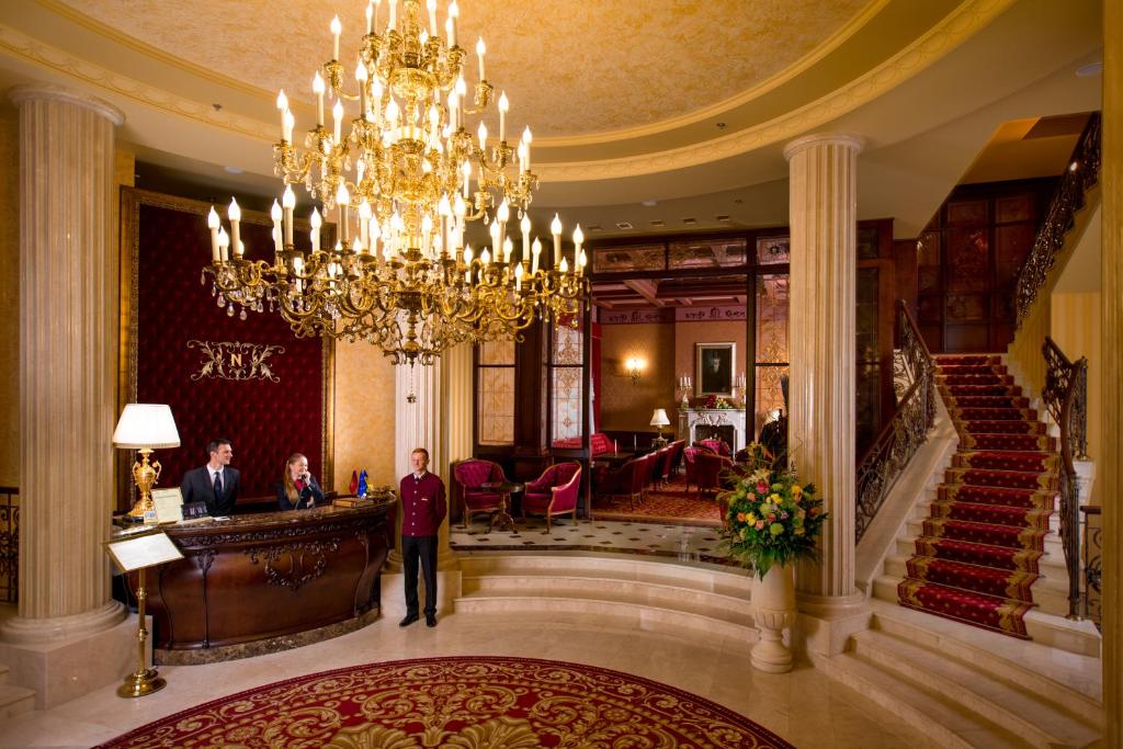 a group of people standing in a lobby with a chandelier at Nobilis Hotel in Lviv