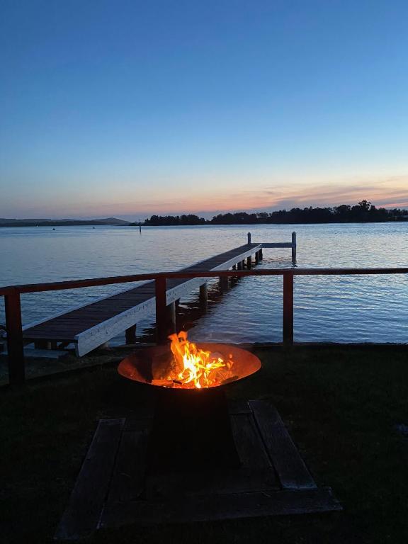 a fire pit next to a dock next to the water at Serenity by the Lake - Romantic Waterfront Couple's Getaway in Marks Point