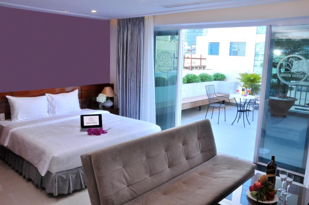 1 dormitorio con cama, sofá y balcón en White Lotus Saigon Hotel, en Ho Chi Minh