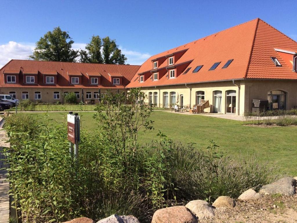 a large building with a red roof on a field at Die Remise Silbersee in Stolpe