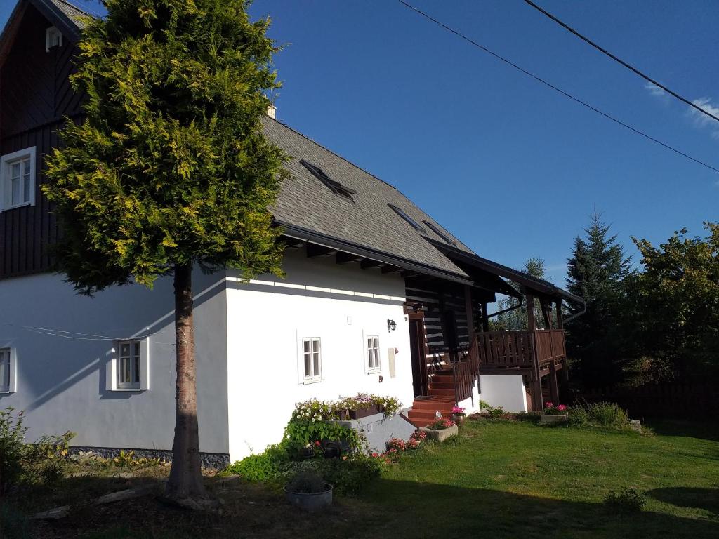 Una casa blanca con un árbol delante. en Chalupa Šiška, en Záhoří