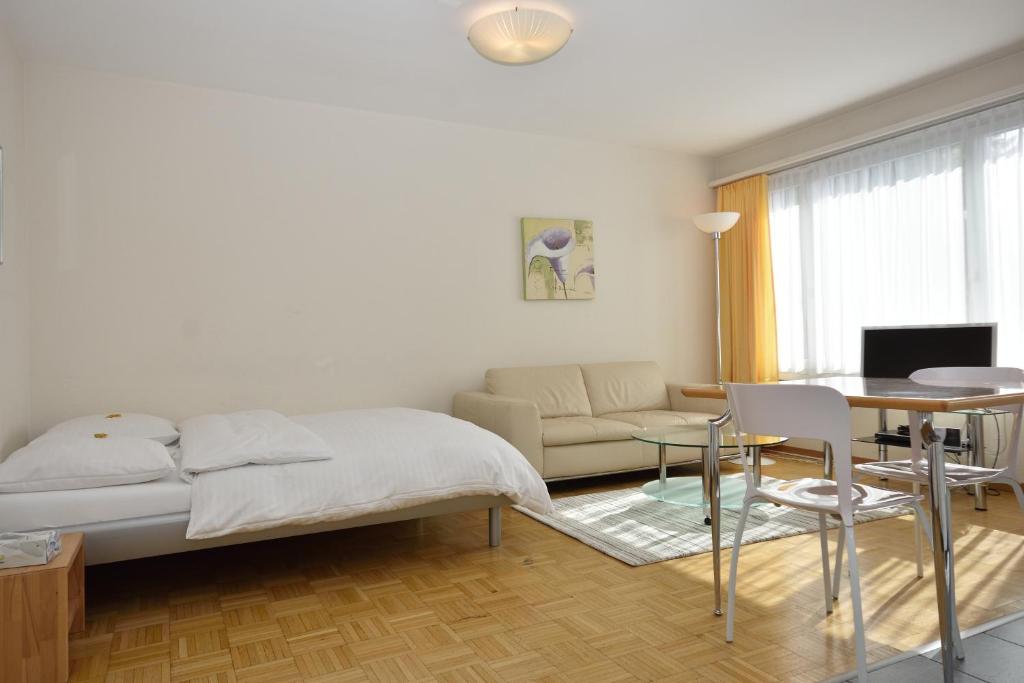 een slaapkamer met een bed, een tafel en een bank bij PABS Résidences - Weinbergstrasse 68 (5MR) in Zürich