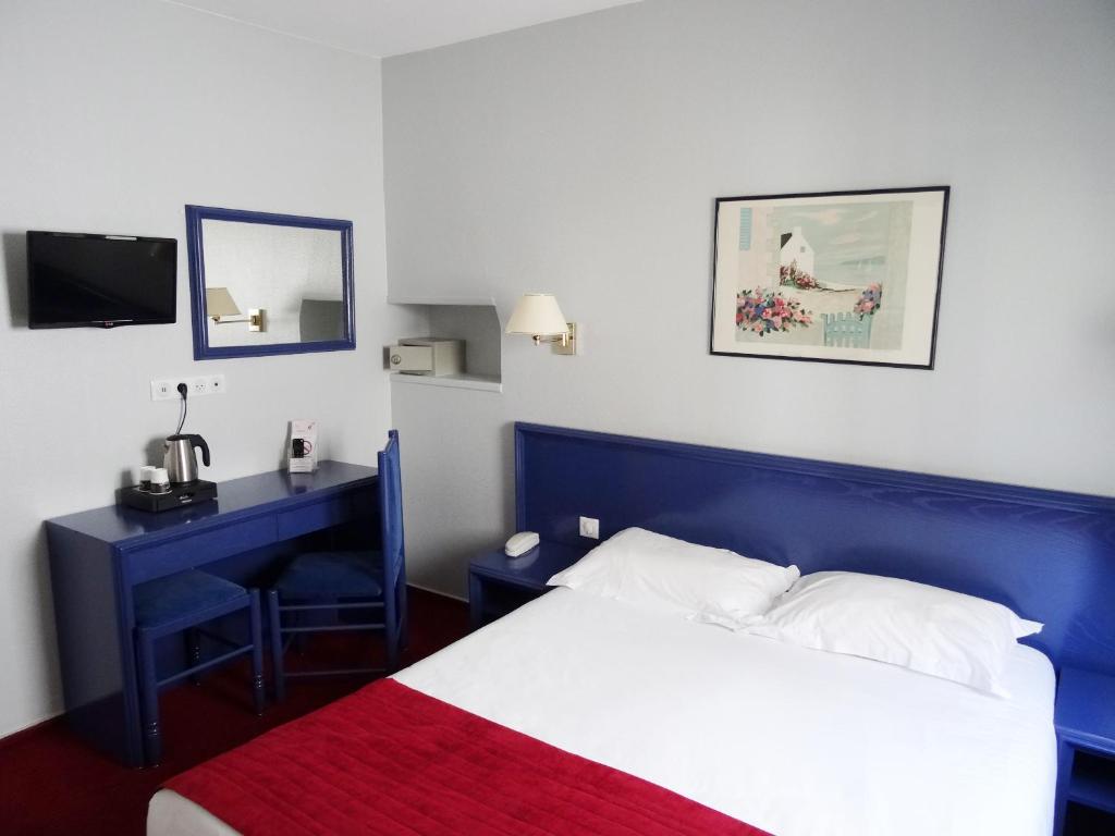 sypialnia z niebieskim łóżkiem i biurkiem z lustrem w obiekcie Résidence du Pré w Paryżu