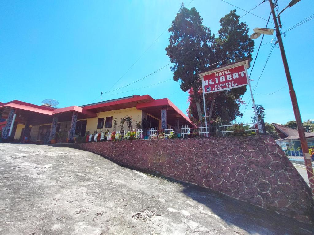 a building with a sign on top of a hill at Hotel Olibert Parapat Ajibata Mitra RedDoorz in Parapat