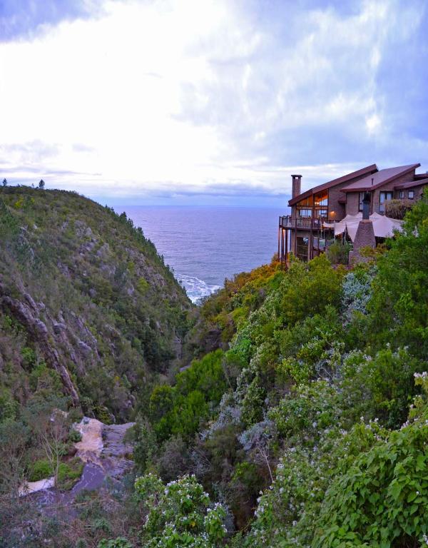 a house on a hill next to the ocean at The Fernery Lodge &amp; Spa in Stormsrivier