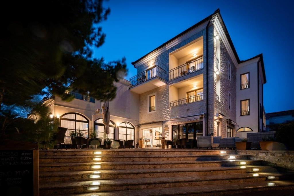 un gran edificio con escaleras delante por la noche en Hotel Nikola, en Vodice