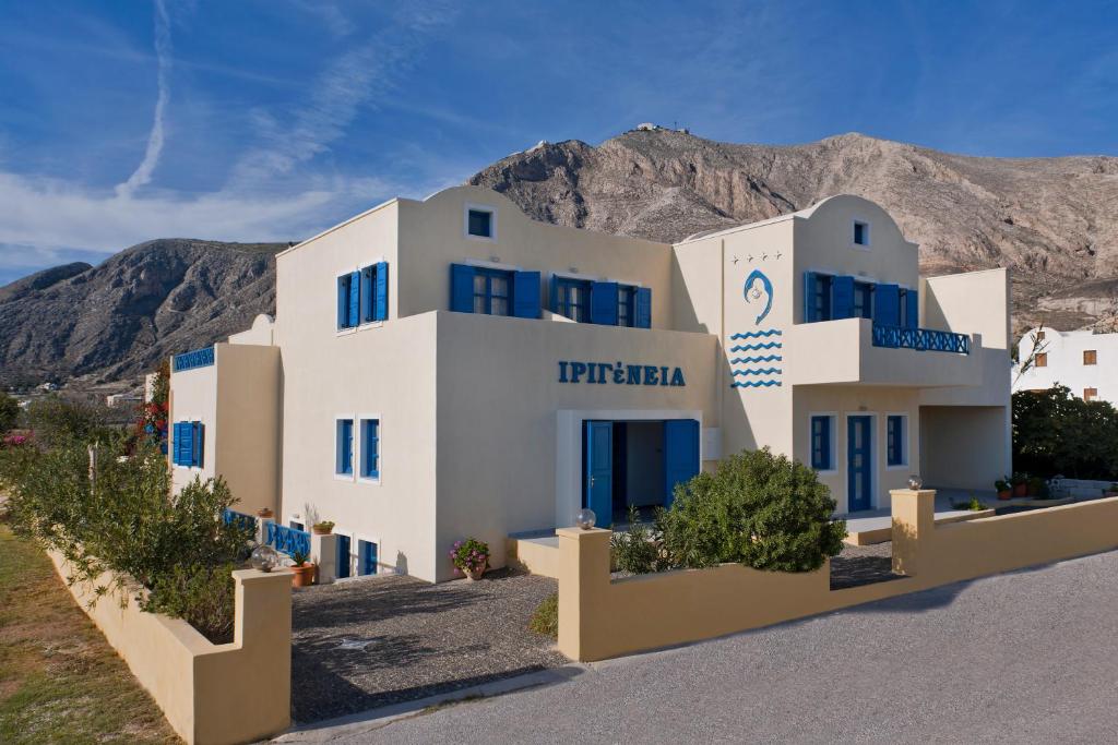 a large white building with a mountain in the background at Irigeneia Hotel in Perissa
