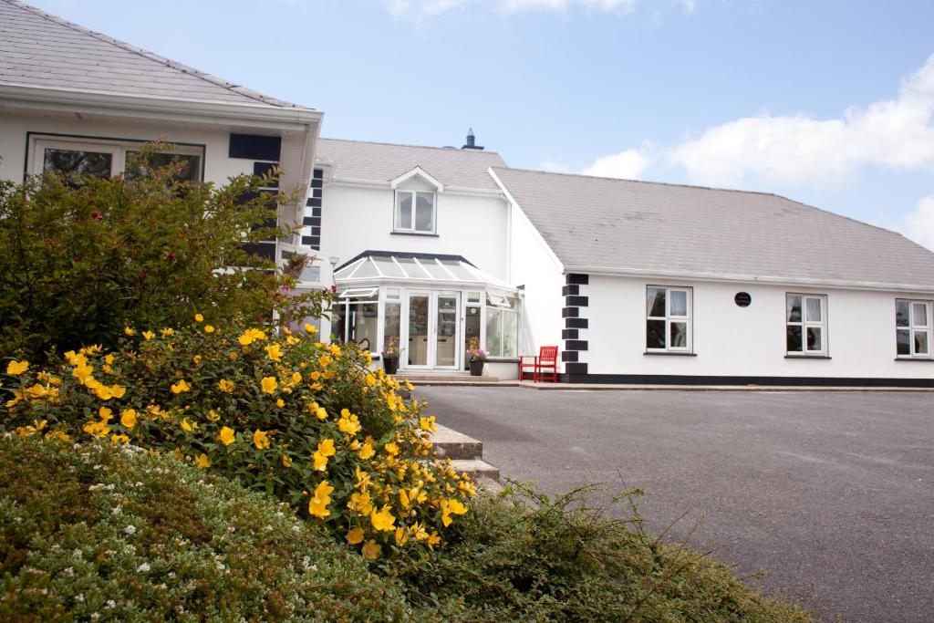 ein weißes Haus mit gelben Blumen davor in der Unterkunft Grovemount House in Ennistymon