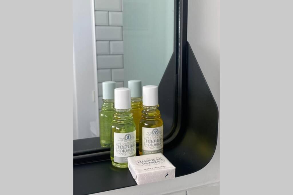 three bottles of oils sitting on a shelf in front of a mirror at Appartement NoBe Es Pujols proche plage, vue mer in Es Pujols