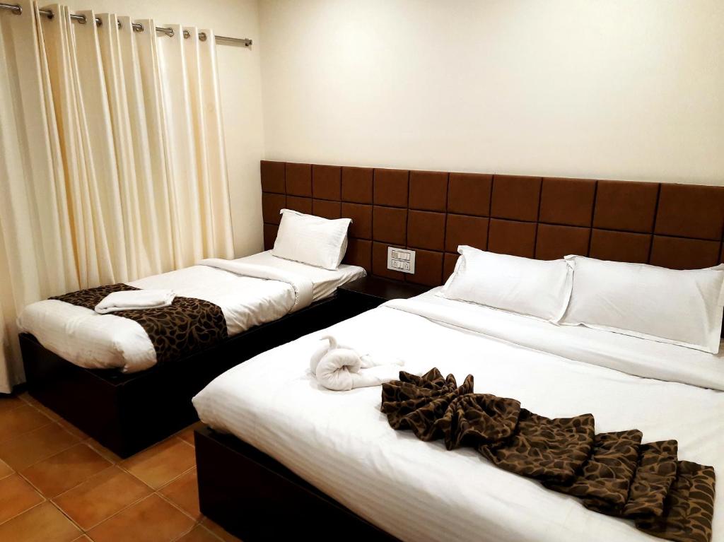 two beds in a hotel room with towels on them at GRAND KODAI SR INN in Kodaikānāl