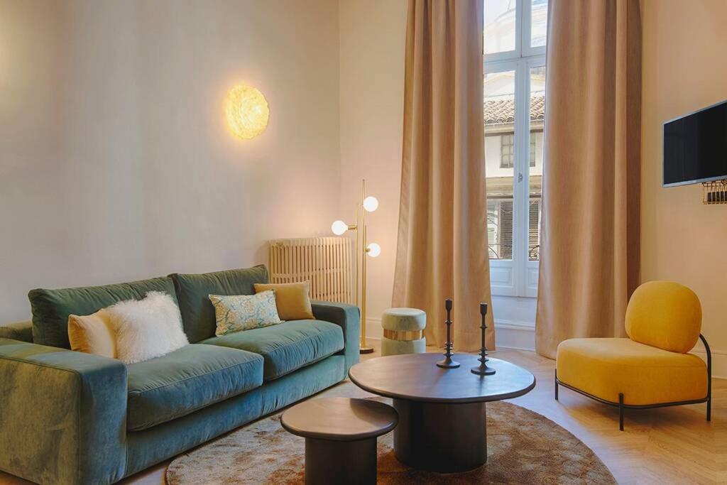 a living room with a green couch and a chair at Romantic Flat in the heart of the city in Avignon