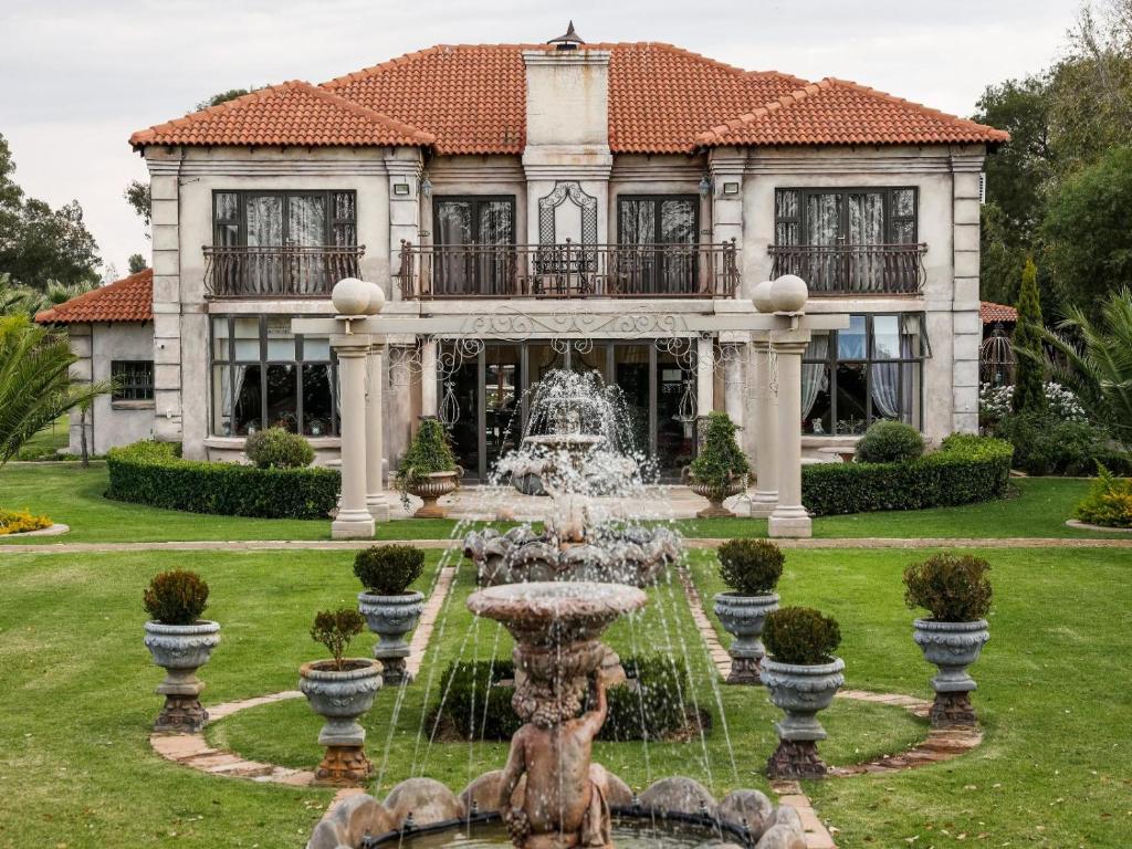 a house with a fountain in front of a building at Tuscan Rose in Bloemfontein