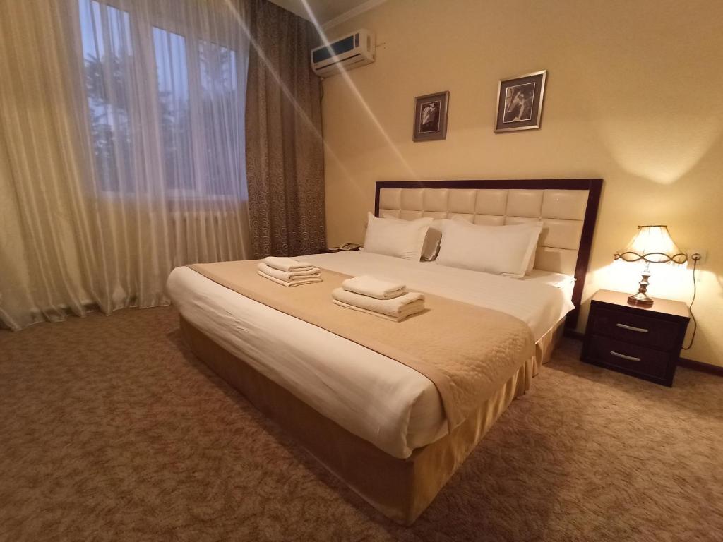 a bedroom with a large bed with towels on it at Silk Way Boutique Hotel in Osh