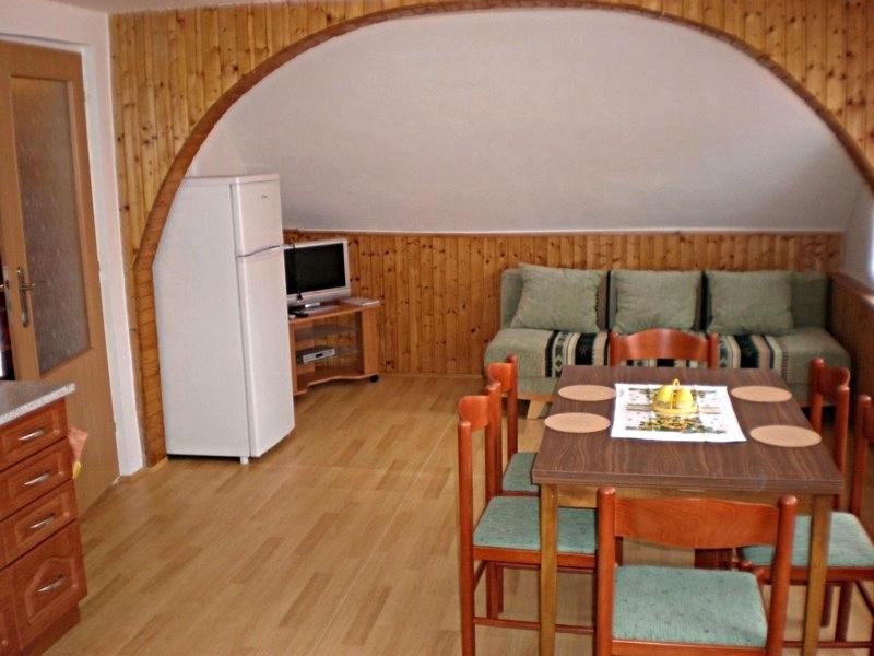 salon ze stołem, kanapą i lodówką w obiekcie Penzion "Apartmány U Semušky" w mieście Pernink
