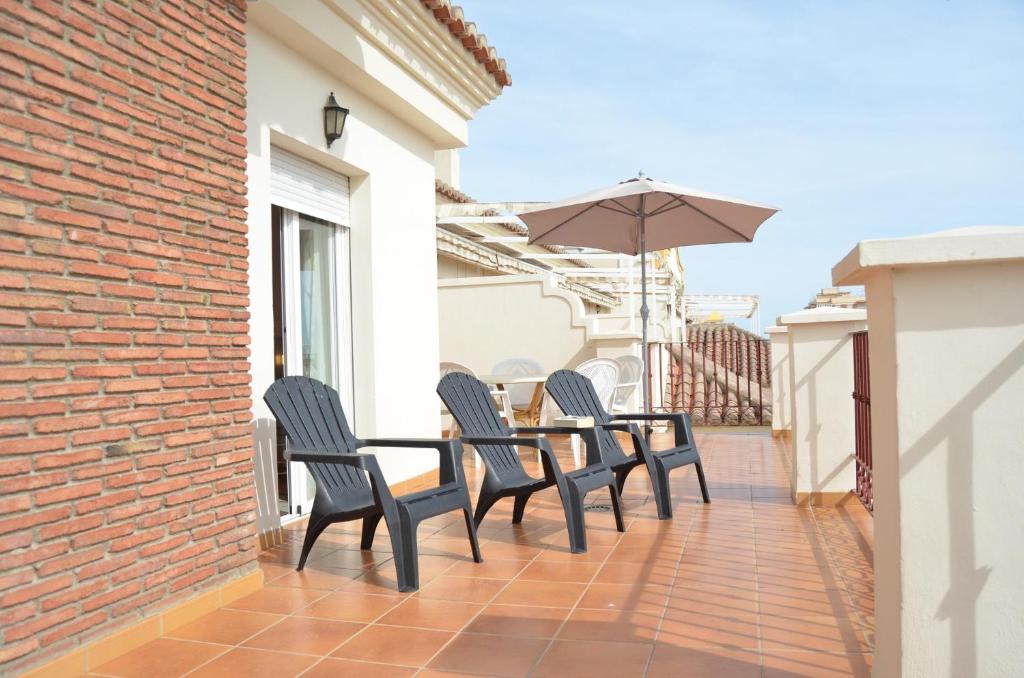 patio ze stołem, krzesłami i parasolem w obiekcie Apartamentos Terrasol AZUCARERA ATICO I w mieście Torre del Mar