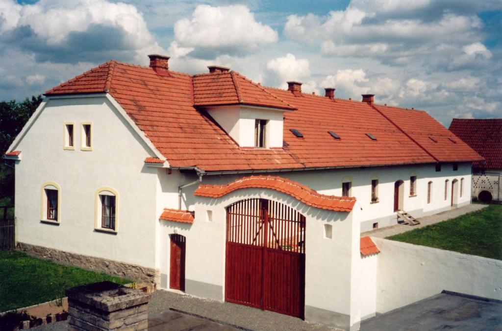 a white house with a red roof with a gate at Blažkův Statek in Malšice