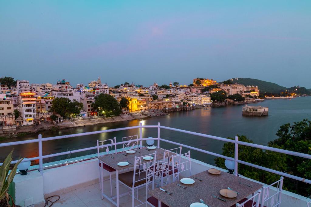 a balcony with a table and a view of a river at Hanuman Ghat Boutique Stays by Cafe Helsinki in Udaipur