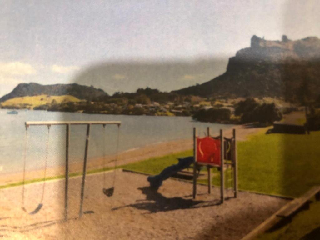 a painting of a swing set next to the water at Taurikura Bay Relax and Explore in Whangarei Heads