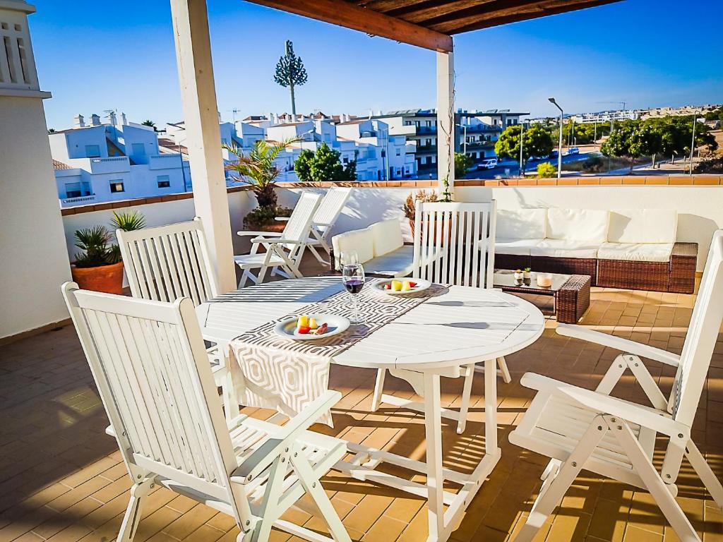 a white dining table and chairs on a balcony at Cabanas Terraces - Pool and seaview in Tavira