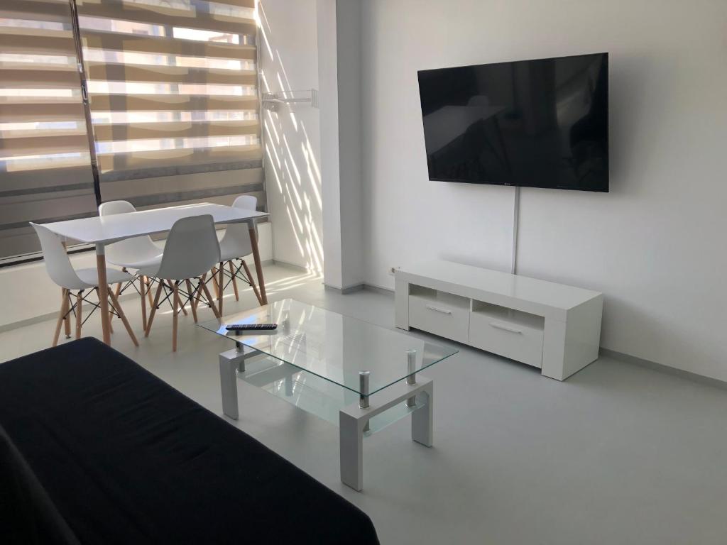 un soggiorno con un tavolo e una TV a parete di APARTAMENTO CENTRAL 1 a Corralejo