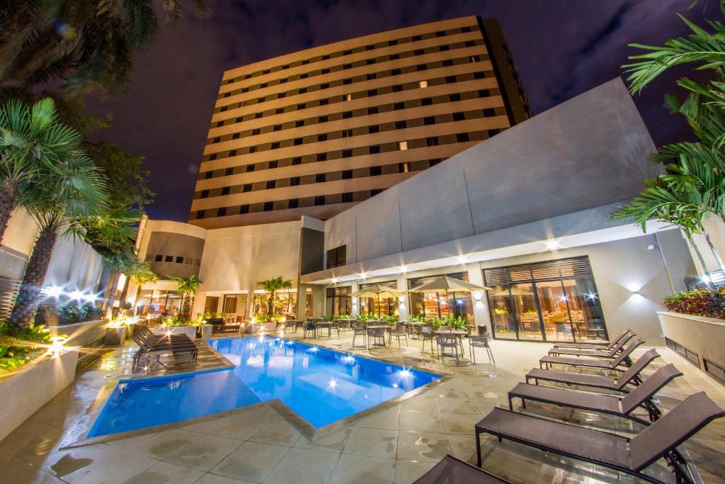 uma piscina de hotel com cadeiras e um edifício em JL Hotel by Bourbon em Foz do Iguaçu