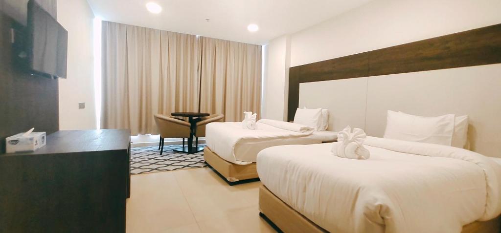 pokój hotelowy z 2 łóżkami i stołem w obiekcie Manazil Aldar Hotel w mieście Suhar