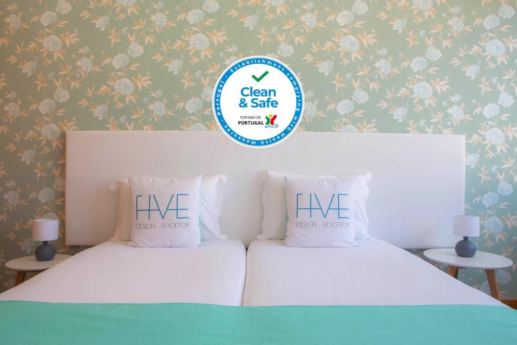 two beds in a bedroom with a sign that says live at Five Design Rooftop by Storytellers in Funchal