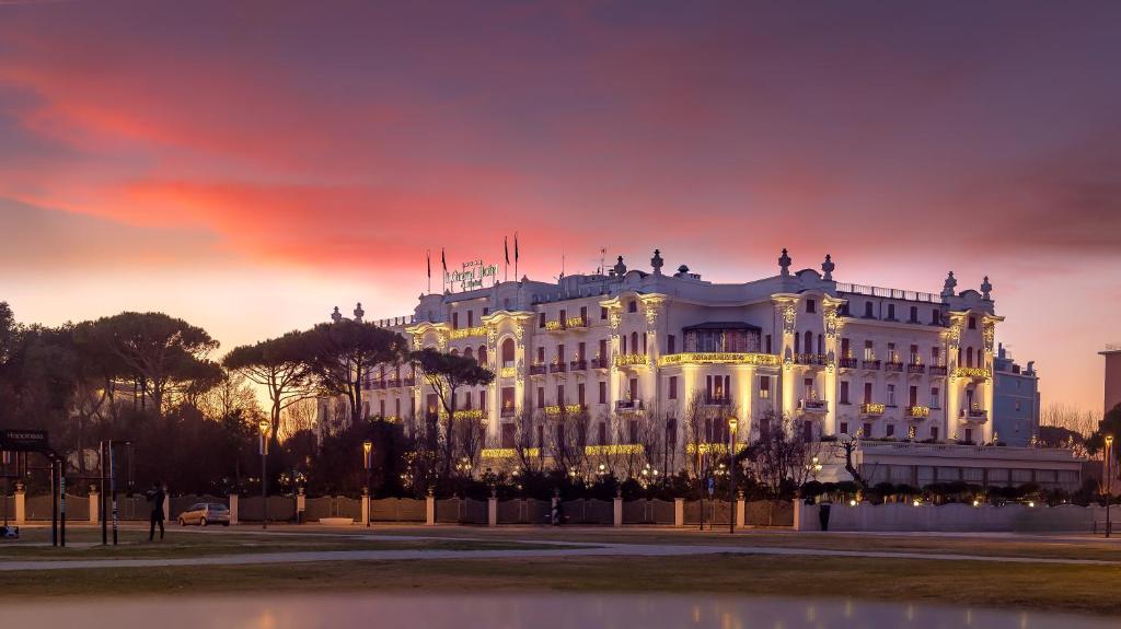 ein weißes Gebäude mit Sonnenuntergang im Hintergrund in der Unterkunft Grand Hotel Rimini in Rimini