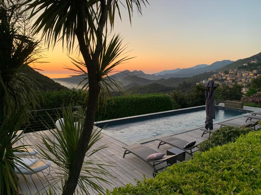 una piscina con sedie e vista sulle montagne di Villa Milanu a Oletta