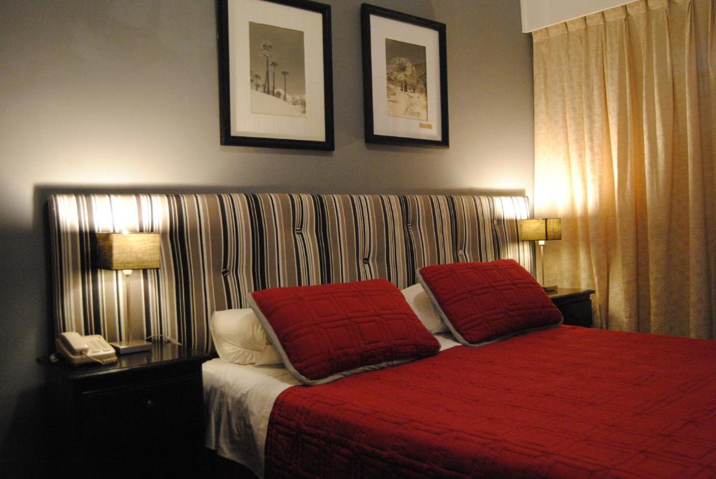 a bedroom with a red bed with two red pillows at Hotel Iberia in Punta del Este