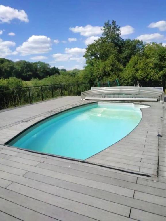 une grande piscine avec une terrasse en bois dans l'établissement Chalet chaleureux à Louâtre avec piscine partagée, à Louâtre