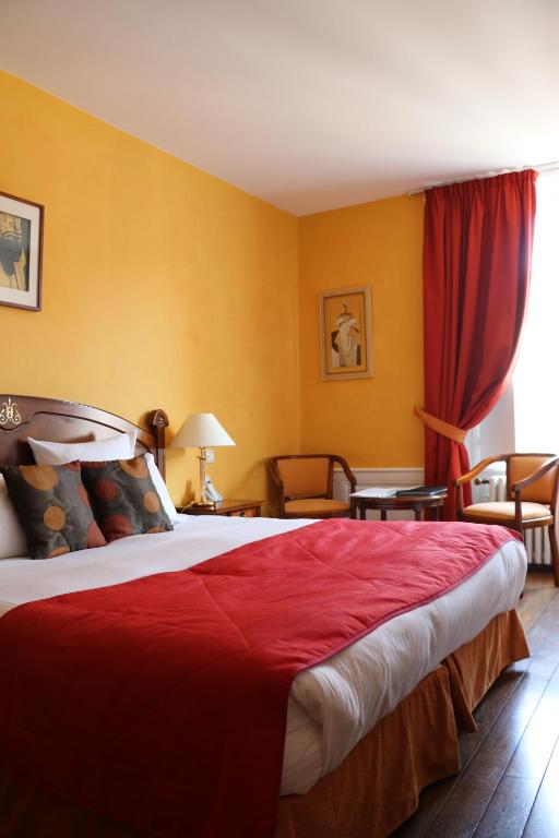 a hotel room with a large bed with red sheets at Hotel D&#39;haussonville in Nancy