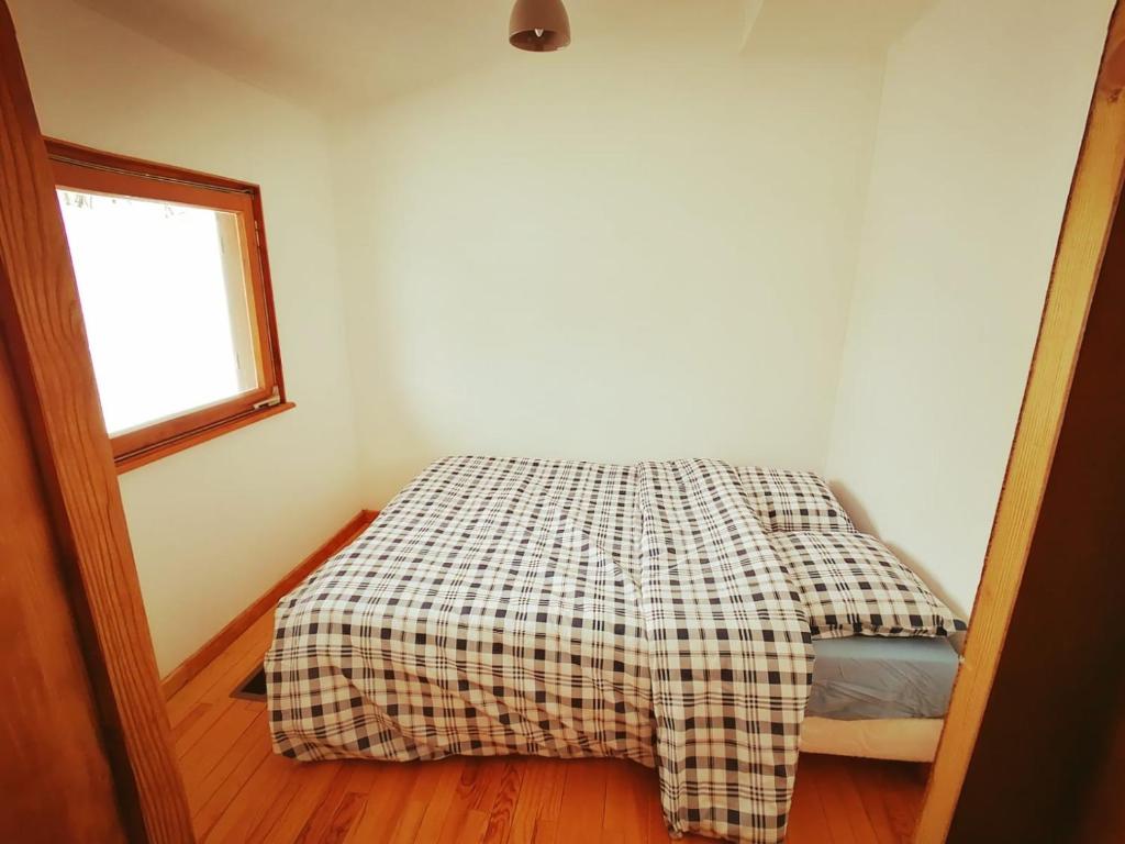 a bedroom with a bed with a checkered blanket at La clé des champs in Colroy-la-Roche