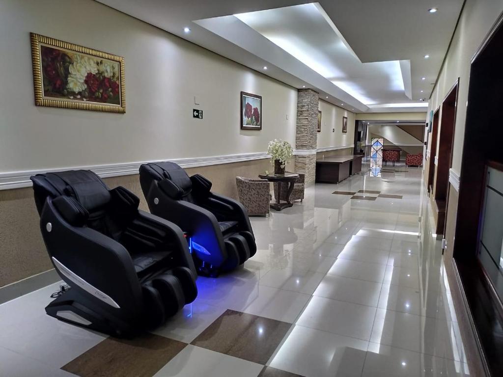 a waiting room with black chairs on a tile floor at Hotel Estação Express in Curitiba