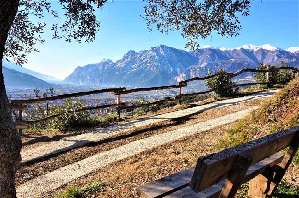 a wooden bench on a hill with a fence and mountains at Chalet Laghel in Arco
